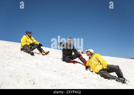 Training zum Korrigieren des Rutschens an Hanglagen oder Gletschern mit Hilfe einer Eispistole. Ein junger Reiseleiter mit Bart erklärt seiner Gruppe, wie man das richtig verlangsamt Stockfoto