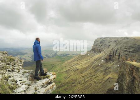 Bärtiger Hipster-Tourist, der am Felsenrand steht und auf einem epischen Plateau in die Ferne blickt. Das Konzept des Tourismus Stockfoto