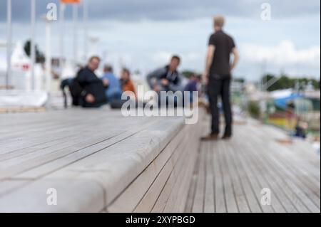 Eine Gruppe von Leuten sitzt auf Holzbänken am Strand von Travemünde Stockfoto