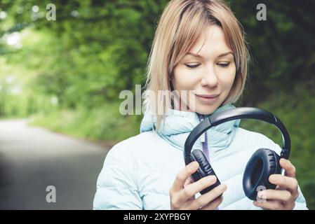 Happy girl im Freien im Wald hält Kopfhörer. Das Konzept der Stereo-Musik überall. Walking Music Stockfoto