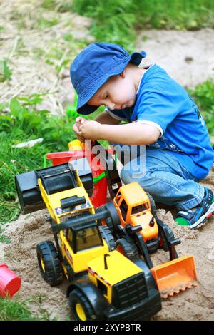 Der süße Junge spielt mit dem Bagger auf dem Spielplatz Stockfoto