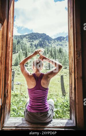 Sportliche Frau auf Wanderung ist die Aussicht genießen, sitzen auf dem Boden einer Berghütte Stockfoto