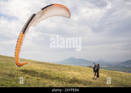 Der Gleitschirmflieger öffnet seinen Fallschirm, bevor er vom Berg im Nordkaukasus abhebt. Füllen Sie den Fallschirmflügel vor dem Start mit Luft Stockfoto