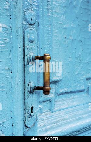 Nahaufnahme von Schlüssellöchern mit Vorhängen und einem Griff auf der blauen, oft gemalten, gerissenen Holztür mit doppeltem Zylinder des letzten Jahrhunderts mit einer Pos. Stockfoto