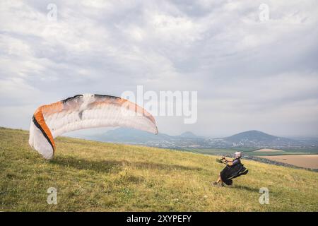 Der Gleitschirmflieger öffnet seinen Fallschirm, bevor er vom Berg im Nordkaukasus abhebt. Füllen Sie den Fallschirmflügel vor dem Start mit Luft Stockfoto
