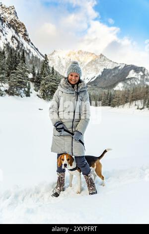 Ein junges Mädchen, das im Winter mit ihrem Beagle-Hund spaziert und beim ersten Mal Spaß auf Schnee hat Stockfoto