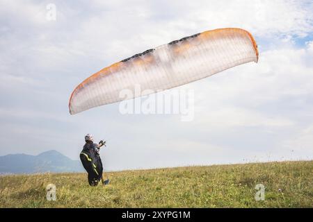 Der Gleitschirmflieger öffnet seinen Fallschirm, bevor er vom Berg im Nordkaukasus abhebt. Füllen Sie den Fallschirmflügel vor dem Start mit Luft Stockfoto