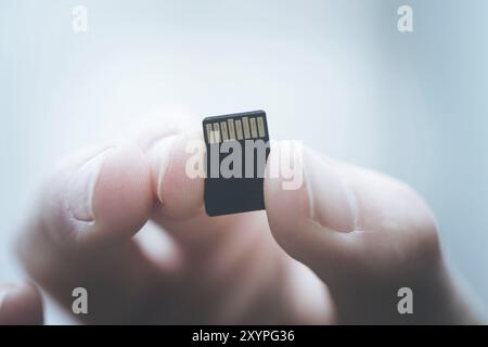 Der junge Mann hält eine kleine Speicherkarte in der Hand, Textraum Stockfoto