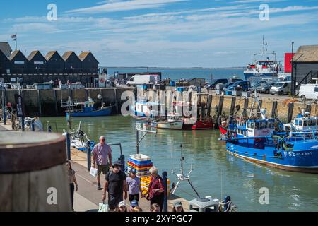Whitstable, Großbritannien - 29. August 2024 Whitstable Hafen in Kent an einem Sommertag bei Ebbe. Es gibt Fischerhütten und Boote sowie Touristen und Einheimische. Die Stockfoto