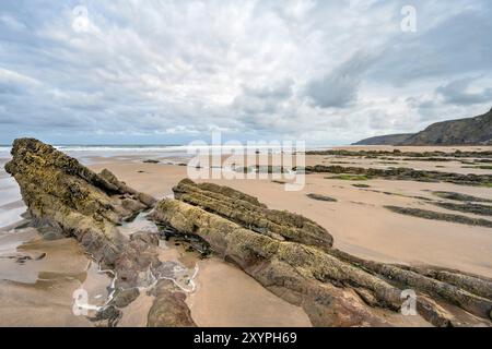 Bei Ebbe tauchen am Sandymouth Beach North West Cornwall im Morgengrauen antike Felsen auf Stockfoto