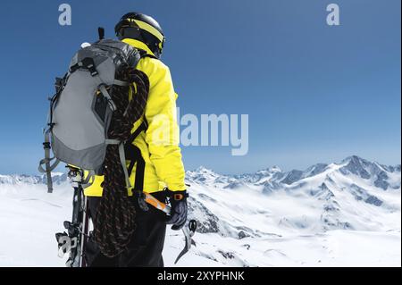 Ein Bergsteiger hält eine Eisaxt hoch in den Bergen, die mit Schnee bedeckt sind. Blick von hinten. Outdoor Extremklettersport im Freien mit Bergsteigen Stockfoto