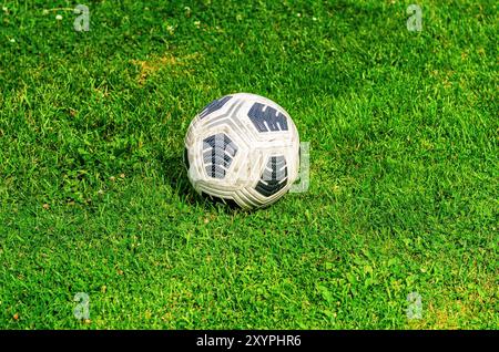 Dreckiger Fußball auf grünem Gras im Freien Stockfoto