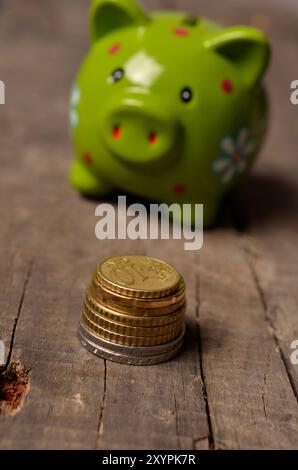 Haufen von Euro-Münzen vor einer grünen Piggy bank Stockfoto