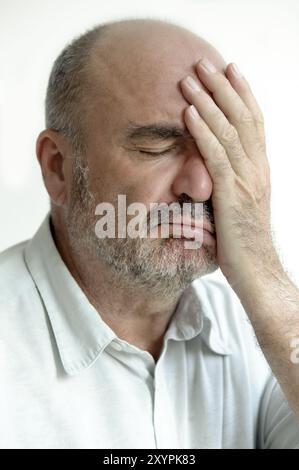 Der Mann bedeckt sein Gesicht mit einer Hand Stockfoto