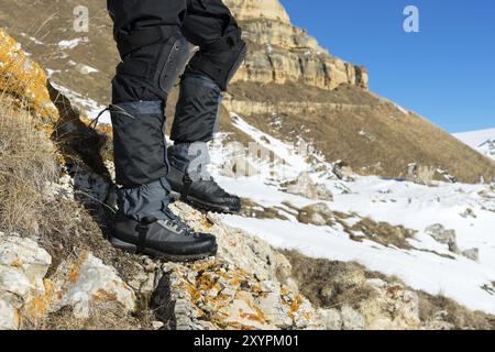 Nahaufnahme des Fußes eines Touristen in Trekkingschuhen mit Stöcken für Nordic Walking auf einem Felsstein in den kaukasischen Bergen Stockfoto