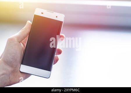 Der Mensch ist ein modernes Smartphone in der Hand, grau Schreibtisch im Hintergrund Stockfoto