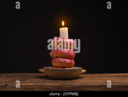 Geburtstag Kuchen mit gestapelten Donuts und eine brennende Kerze Stockfoto