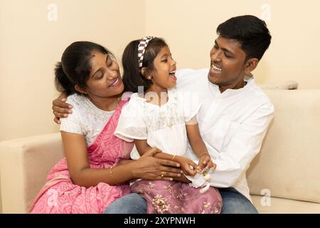 Eine Mutter und ein Vater interagieren freudig mit ihrer kleinen Tochter, teilen Lachen und Wärme in ihrem komfortablen Wohnraum und schaffen eine glückliche Familie Stockfoto