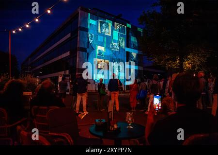 Arnhem, Gelderland, Niederlande. August 2024. Bilder von Zeugenaussagen aus dem Zweiten Weltkrieg werden über das Rathaus projiziert. An die 80. Schlacht von Arnheim erinnert man, in der Abenddämmerung erleuchten spezielle Projektionen Gebäude im Stadtzentrum. Die Schlacht bei Arnheim wurde während der Operation Market Garden ausgetragen. Die Operation Market sollte die deutschen Truppen überraschen und Arnheim und seine wichtigen Brücken über den Rhein erobern, bevor sie von den Verteidigern zerstört werden konnten. Es war der größte Luftangriff in der Geschichte und einer der ehrgeizigsten alliierten Operationen des Zweiten Weltkriegs. Stockfoto