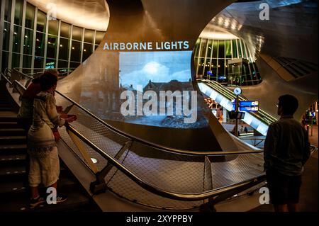 Arnhem, Gelderland, Niederlande. August 2024. Die Leute sehen die Bilder, die auf eine Säule des Gebäudes projiziert werden. An die 80. Schlacht von Arnheim erinnert man, in der Abenddämmerung erleuchten spezielle Projektionen Gebäude im Stadtzentrum. Die Schlacht bei Arnheim wurde während der Operation Market Garden ausgetragen. Die Operation Market sollte die deutschen Truppen überraschen und Arnheim und seine wichtigen Brücken über den Rhein erobern, bevor sie von den Verteidigern zerstört werden konnten. Es war der größte Luftangriff in der Geschichte und einer der ehrgeizigsten alliierten Operationen des Zweiten Weltkriegs. (Credi Stockfoto