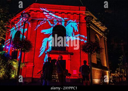 Arnhem, Gelderland, Niederlande. August 2024. Das Symbol der Airborne Division wird auf die Fassade eines Gebäudes projiziert. An die 80. Schlacht von Arnheim erinnert man, in der Abenddämmerung erleuchten spezielle Projektionen Gebäude im Stadtzentrum. Die Schlacht bei Arnheim wurde während der Operation Market Garden ausgetragen. Die Operation Market sollte die deutschen Truppen überraschen und Arnheim und seine wichtigen Brücken über den Rhein erobern, bevor sie von den Verteidigern zerstört werden konnten. Es war der größte Luftangriff in der Geschichte und einer der ehrgeizigsten alliierten Operationen der Zweiten Welt Stockfoto