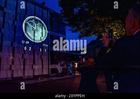 Arnhem, Gelderland, Niederlande. August 2024. Auf die Fassade des Rathauses wird ein Countdown-Bild projiziert. An die 80. Schlacht von Arnheim erinnert man, in der Abenddämmerung erleuchten spezielle Projektionen Gebäude im Stadtzentrum. Die Schlacht bei Arnheim wurde während der Operation Market Garden ausgetragen. Die Operation Market sollte die deutschen Truppen überraschen und Arnheim und seine wichtigen Brücken über den Rhein erobern, bevor sie von den Verteidigern zerstört werden konnten. Es war der größte Luftangriff in der Geschichte und einer der ehrgeizigsten alliierten Operationen des Zweiten Weltkriegs Stockfoto