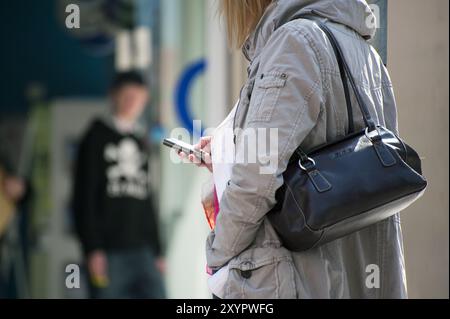 Weibliche Person in Seitenansicht, die eine Textnachricht sendet Stockfoto