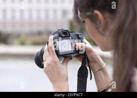 Das junge, schöne Mädchen macht ein Foto mit ihrer Kamera. Blick von hinten Stockfoto