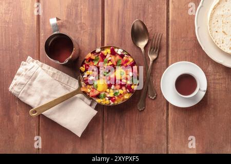 Mexikanisches Frühstück. Huevos Rancheros, die Spiegeleier, von oben mit dem Pico de gallo Salat, heißer Schokolade und Tortillas auf einem dunklen rustikalen Woo geschossen Stockfoto