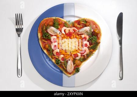 Farbenfrohe, appetitliche Pizza in Herzform mit Garnelen auf einem Teller exotisches, konzeptionelles Food Stillleben Stockfoto