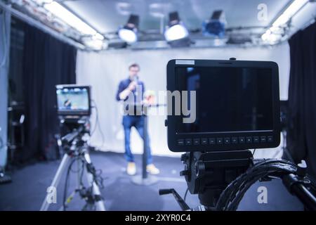 Männlicher Journalist in einem Fernsehstudio spricht in ein Mikrofon, Filmkameras Stockfoto