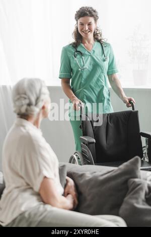 Attraktive junge Krankenschwester mit Rollstuhl-Seniorin Stockfoto