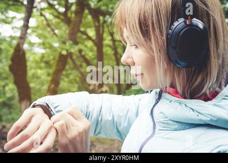 Porträt Junge Fitness-Frau, die ihre Smartwatch ansieht, während sie eine Pause vom Sporttraining macht. Sportsfrau überprüft Puls auf Fitness-Smartwatch d Stockfoto