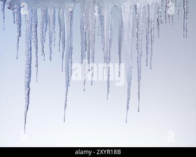 Schmelzende Eiszapfen auf hellblauem Hintergrund isoliert Stockfoto