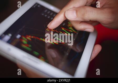 Makroaufnahme ein Mann, der die Börse auf Tablet, Smartphone überprüft Stockfoto