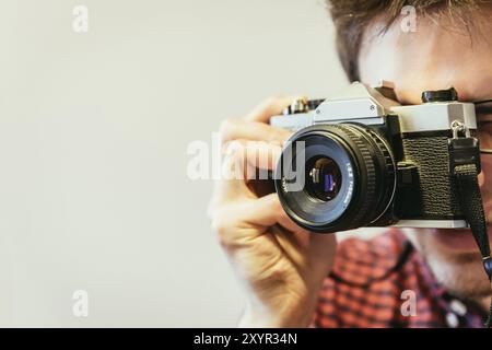 Junger Mann in rot-blau kariertes Hemd ist ein Bild mit einem Vintage Kamera, retro style Stockfoto
