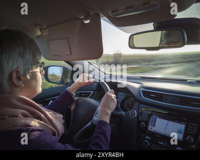 Seniorin fährt ein Auto gegen das Licht Stockfoto