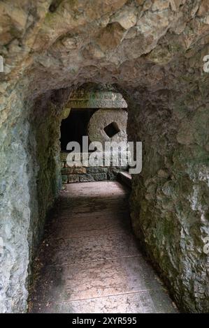 Großer runder Deckstein in einer Höhle, Teil des Kreuzweges entlang der Straße zum Madonna della Corona-Heiligtum in der Nähe des Dorfes Spiazzi in der Stockfoto