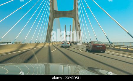 Lissabon, Portugal, 3. August 2024. Autos fahren über die berühmte Vasco da Gama-Brücke unter klarem blauen Himmel. Stockfoto