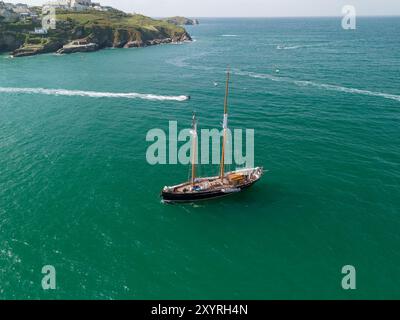 Aus der Vogelperspektive einer klassischen Segelyacht, die einen sonnigen Tag auf dem türkisfarbenen Wasser in der Nähe von newquay, cornwall, einem beliebten Surfziel, genießt Stockfoto