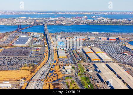 Aus der Vogelperspektive eines geschäftigen Industriegebiets und einer Brücke über einen Fluss in New York City, aufgenommen von einem Flugzeugfenster. Stockfoto