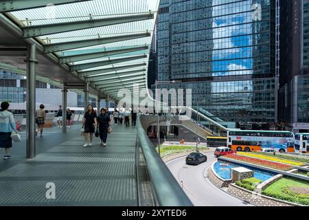 Hongkong, China - 03. Juli 2024 : Fußgänger gehen auf einem erhöhten Gehweg in Hongkong, China. Der Fußweg ist mit einem Glasdach bedeckt und es gibt dort auch Stockfoto