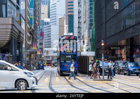 Hongkong, China - 03. Juli 2024 : Eine Straßenbahn in Hongkong im Zentrum von Hongkong, mit Menschen, die die Straße davor überqueren. Stockfoto