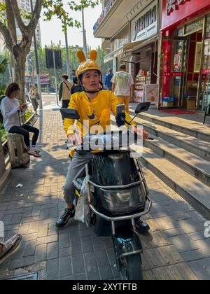 Shanghai, China, Chinese Food Delivery man, fahrender Motorroller auf dem Bürgersteig, Straßenszene Stockfoto