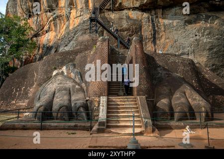 Touristen spazieren zwischen den Löwenpfoten auf der Löwenplattform an der Sigiriya Felsenfestung in Sri Lanka. Stockfoto