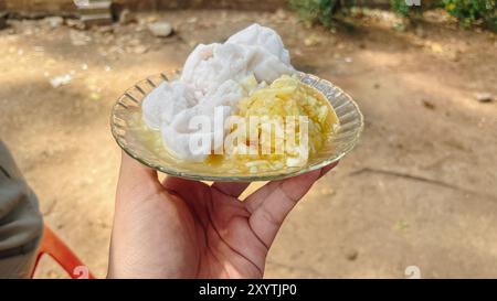 Eine Person hält einen Teller mit einer traditionellen indonesischen Küche namens Rujak. Das Dessert besteht aus Obstscheiben mit leichter Brühe. Stockfoto