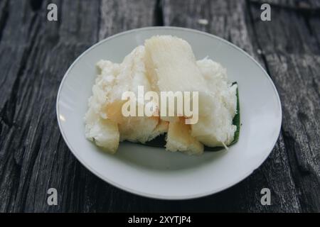 Gekochter Maniok oder telo, traditioneller indonesischer Snack, serviert auf Bananenblatt und weißem Teller. Stockfoto