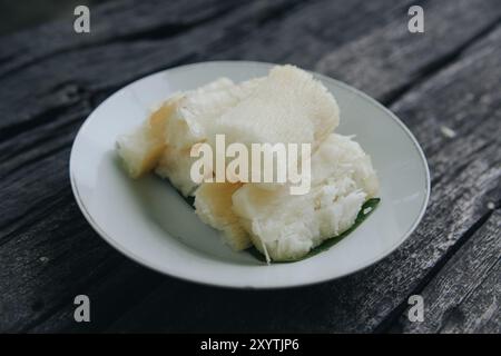 Gekochter Maniok oder telo, traditioneller indonesischer Snack, serviert auf Bananenblatt und weißem Teller. Stockfoto