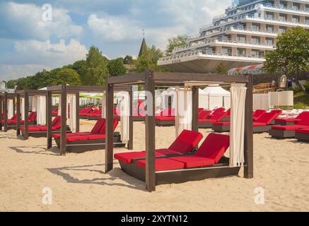 Leere Liegen in einer Reihe am Sandstrand und Hostel Stockfoto