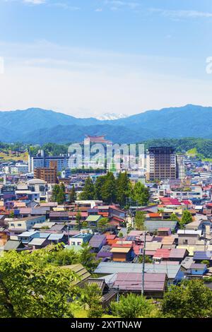 Takayama, Japan, 11. Juli 2015: Schneebedeckte Bergkette rund um die Gebäude der Innenstadt an einem sonnigen Sommertag. Vertikal, Asien Stockfoto